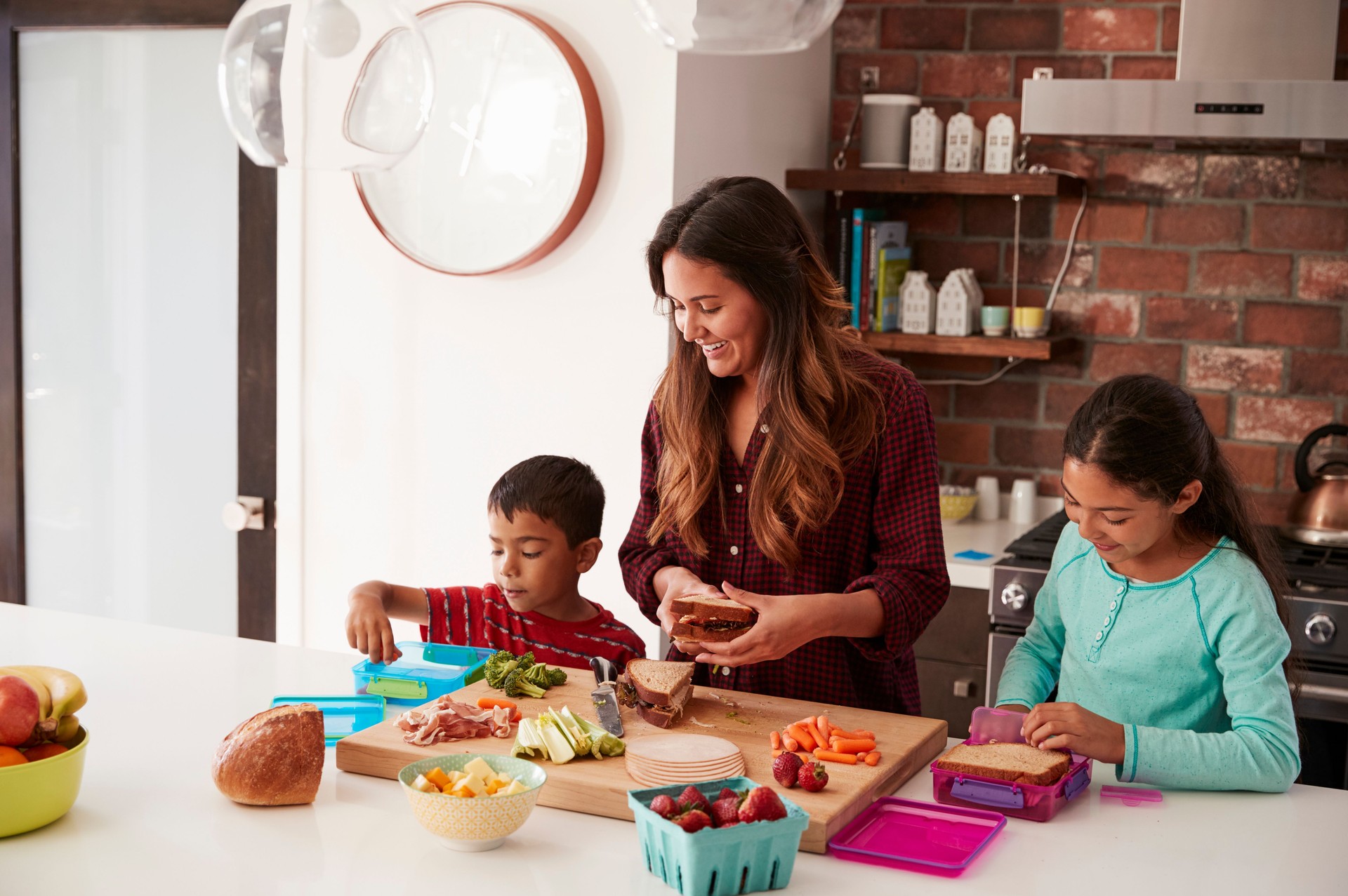 Children Helping Mother To Make School Lunches In Kitchen At Home