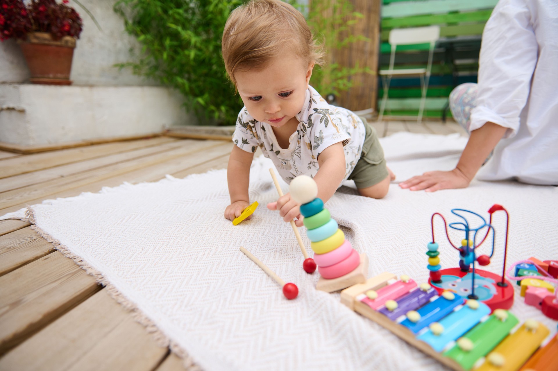 Baby playing with colorful toys on outdoor patio